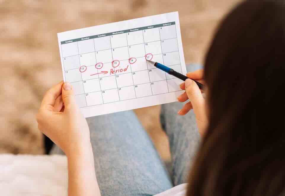 Lady marks the days in the calendar menstrual cycle to track the symptoms of pregnancy after sex.