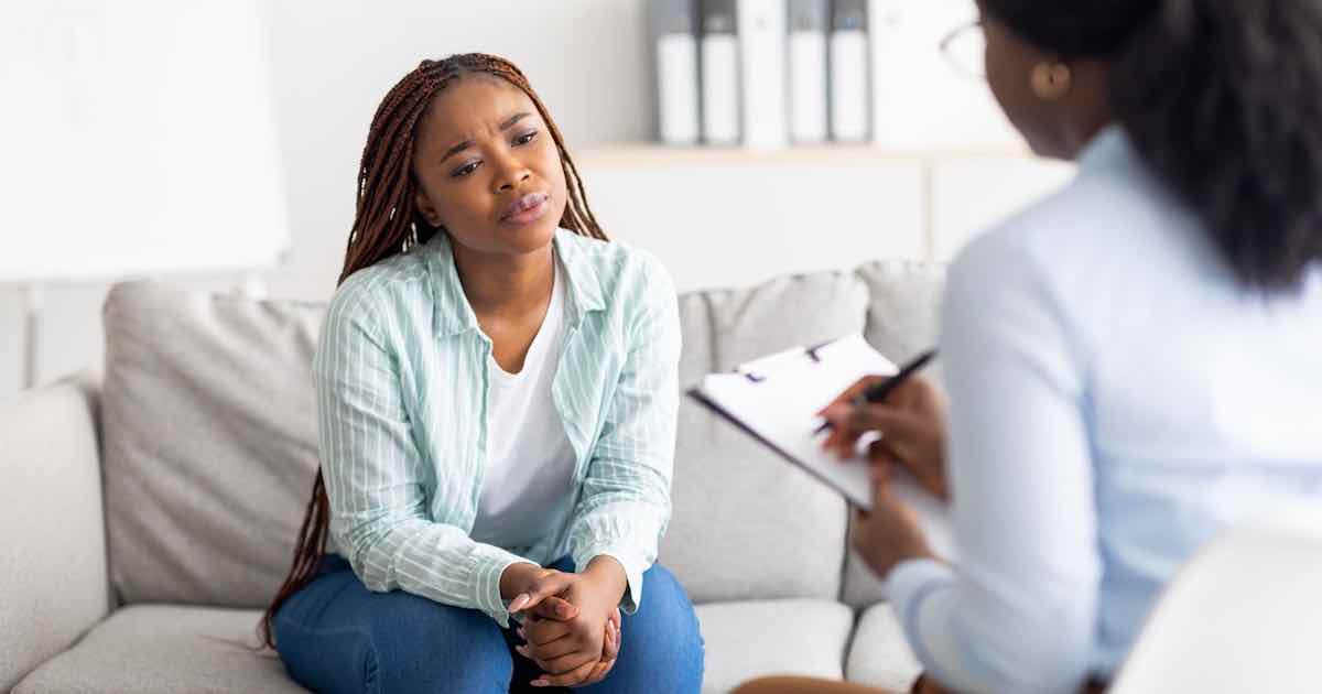 Anxious black woman speaking with a doctor at a clinic receiving professional medical help about how to get tested for STDs.