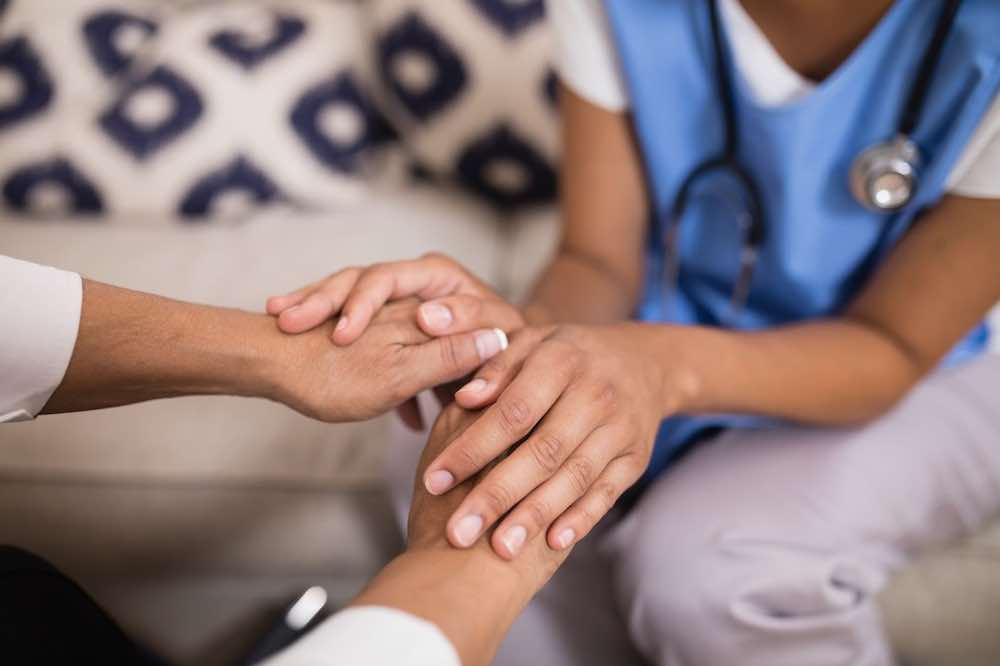 Mid section of doctor touching patient’s hands, giving information about “Can I get an abortion in Oklahoma?”