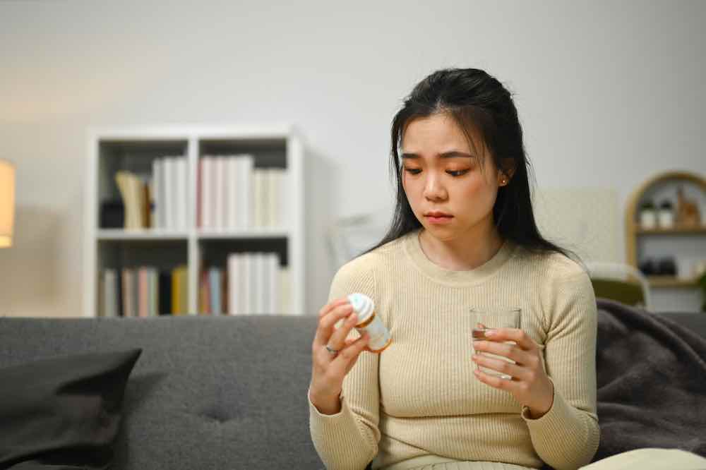 Upset young woman wondering whether to take a pill that blocks progesterone.
