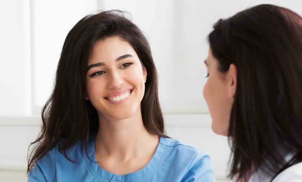 Nurse in blue scrubs talking a patient through the process of how long do STD results take.