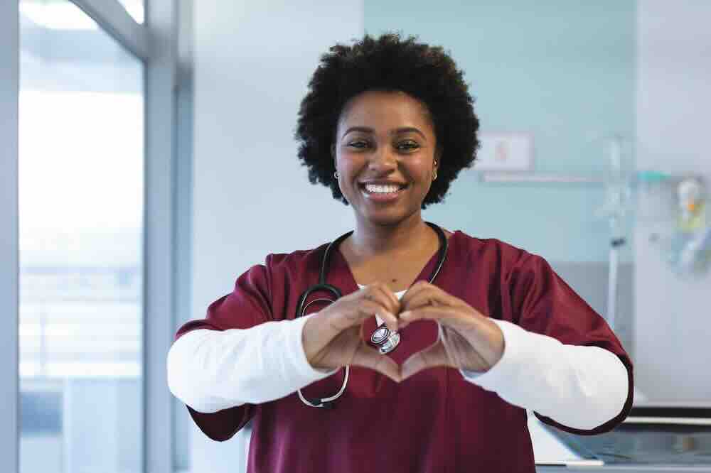 Nurse in maroon scrubs making heart hands and providing info like “What’s the most likely STD to get?”