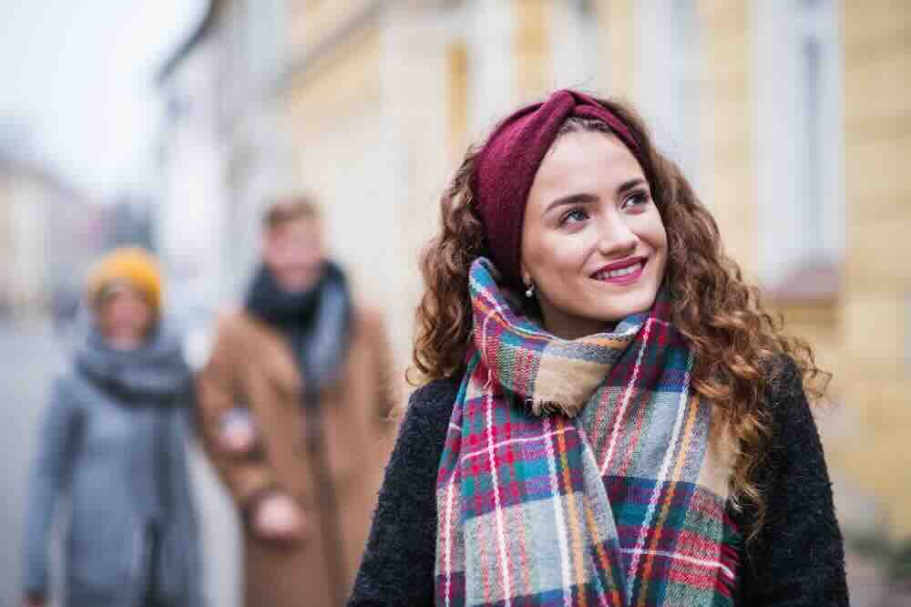 Girl with a plaid scarf walking outdoors and wondering “what are common symptoms of STDs?”