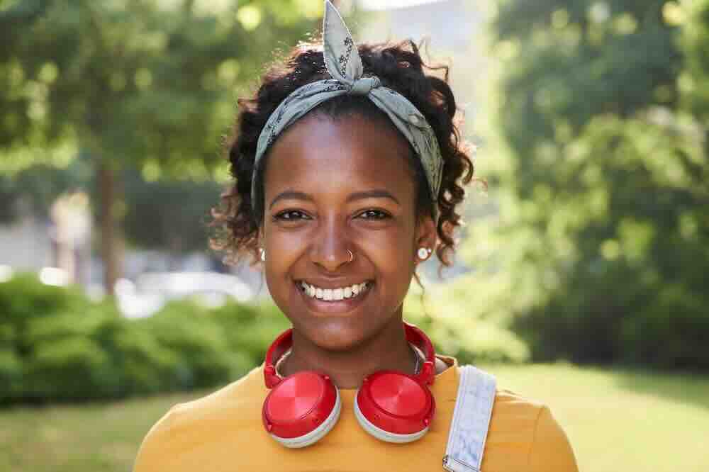 Happy woman outdoors with red headphones researching how common is syphilis in Missouri.