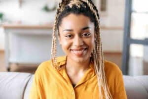 Happy woman with braids in a yellow shirt asking what does a full STD test include?