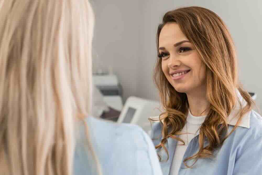 Woman in a blue shirt asking a nurse, “What does a full STD test include?”