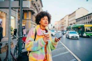 Woman wearing a colorful jacket and holding a phone, asking “where is the easiest place to get tested for STDs?”