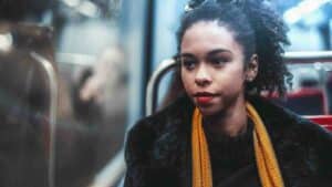 Woman with a yellow scarf riding the bus and wondering “what are common symptoms of STDs?”