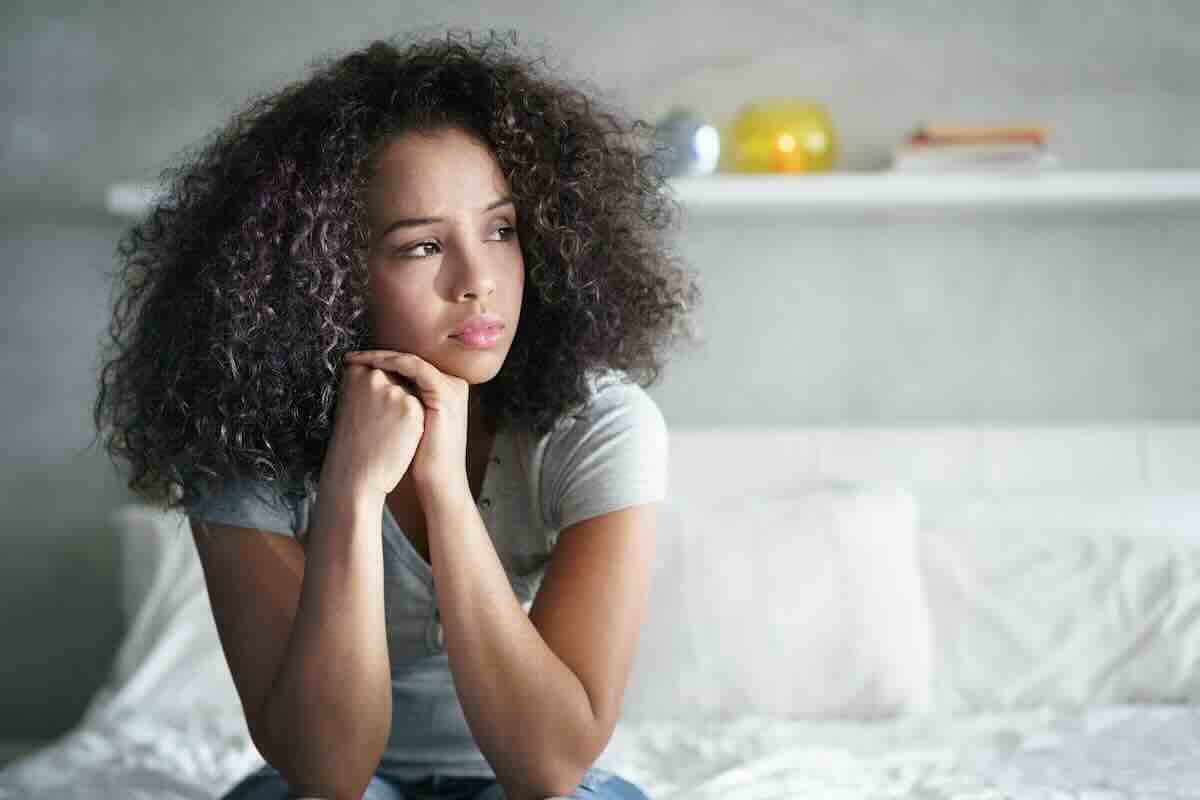 Worried girl on couch wondering about abortion pills side effects.